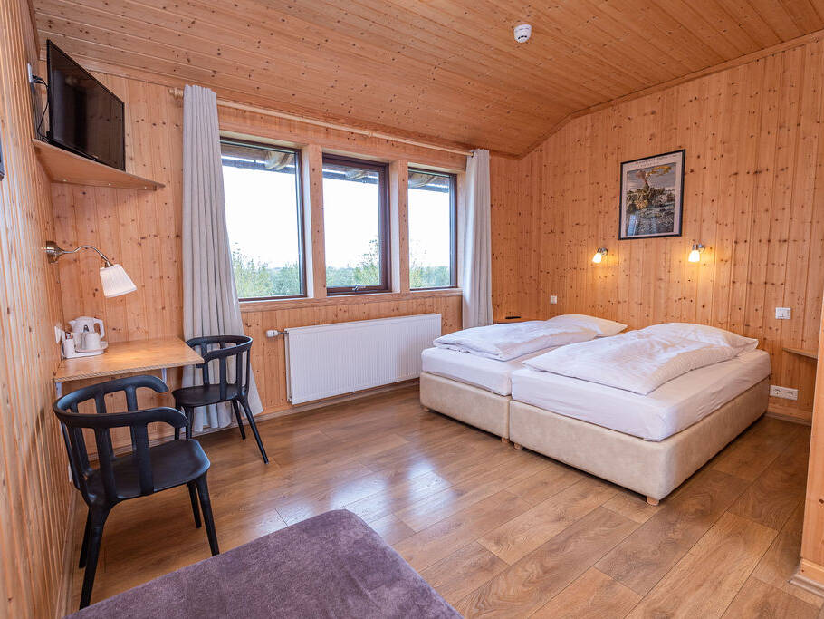 Arnanes Country Hotel A small wooden room with twin beds, a wall-mounted telly, desk with chair, lamp, kettle, and a window with curtains. Hofn South Iceland