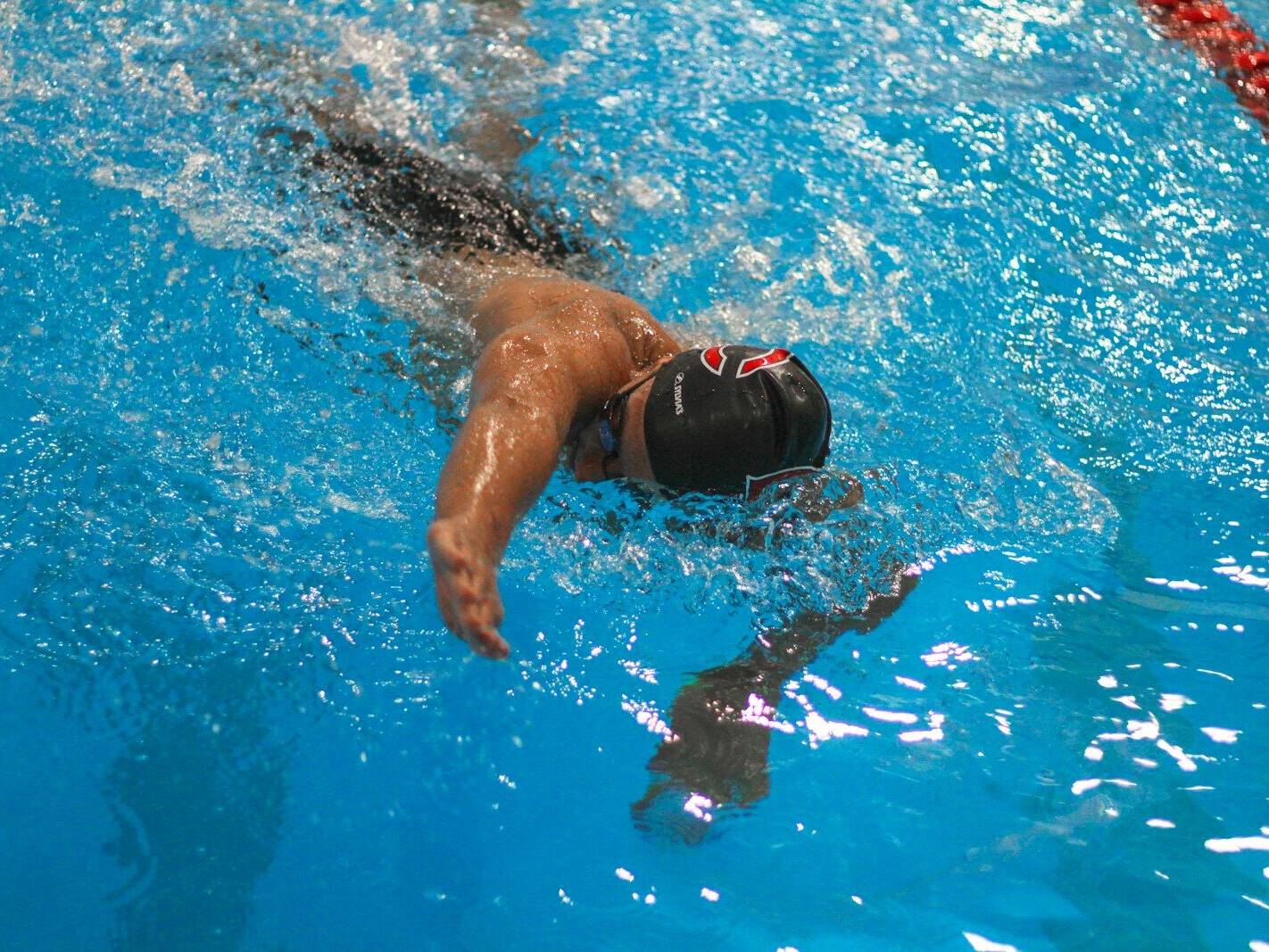 a man swimming in a pool with a hat on